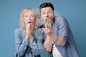 Two astonished man and woman in full disbelief, keeping mouths opened