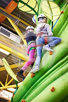 Two athlete girls climbing on artifical green tree