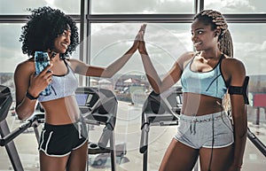 Two athlete woman giving high five in the gym