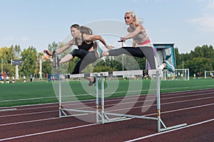 Two athlete woman runnner running hurdles