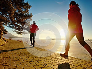 Two athletes couple run together in spring lake landscape