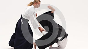 Two athletes performing aikido using bokken. Isolated, white. Close up. Slow motion.