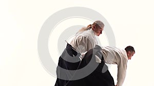 Two athletes performing aikido using bokken. Isolated, white. Close up. Slow motion.
