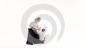 Two athletes performing aikido using bokken. Isolated, white. Slow motion.