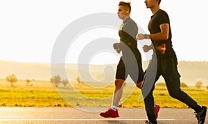 Two athletes running at sunset. Backlit silhouette of two friends training together.