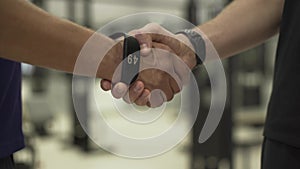 Two athletes shaking hands standing in front of fitness equipment in the gym. Concept of sport, active lifestyle