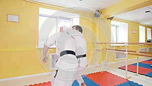 Two athletic men training their aikido skills in the studio. Parries the hit and throwing the opponent on the floor