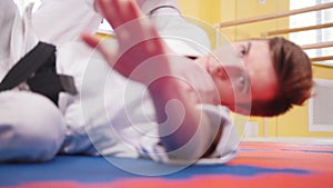 Two athletic men training their aikido skills in the studio. Throwing the opponent on the floor and he hitting the floor