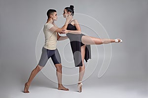 Two athletic modern ballet dancers are posing against a gray studio background.