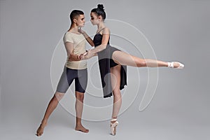 Two athletic modern ballet dancers are posing against a gray studio background.