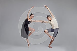 Two athletic modern ballet dancers are posing against a gray studio background.