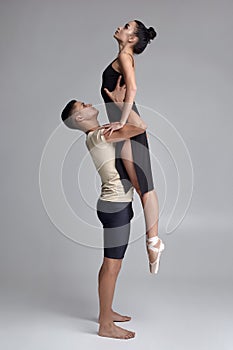 Two athletic modern ballet dancers are posing against a gray studio background.