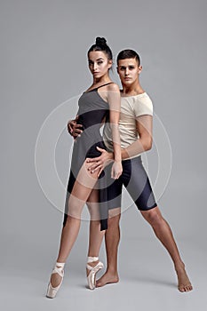 Two athletic modern ballet dancers are posing against a gray studio background.