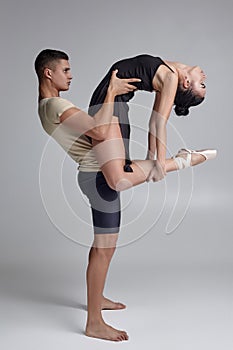 Two athletic modern ballet dancers are posing against a gray studio background.