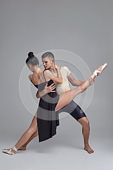 Two athletic modern ballet dancers are posing against a gray studio background.