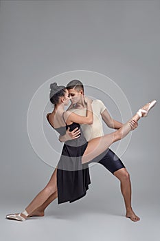 Two athletic modern ballet dancers are posing against a gray studio background.