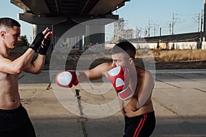 Two athletic young men boxing . Men training outdoors