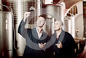 Two attentive men coworkers wearing uniform standing with glass