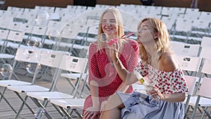 Two attractive beautiful young blond women blow bubbles in the park and are happy on sunset. Girlfriends in park. Slow motion