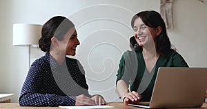 Two attractive friendly women colleagues talking in office at workplace