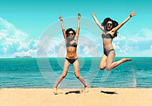 Two Attractive Girls in Bikinis Jumping on the Beach. Best Friends Having Fun, Summer vacation holiday Lifestyle. Happy