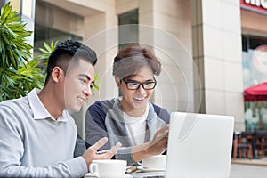 Two attractive mature students talking and working outdoors on l