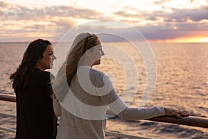 Two Attractive middle-aged women enjoying the sunset view from the deck of a cruise ship