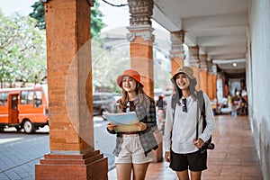 two attractive women carrying a map looking for tourist destinations