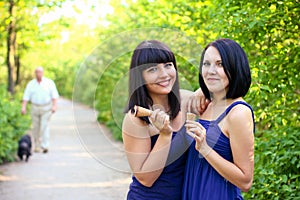 Two attractive women with ice cream in the summer park