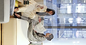 Two attractive women talking seated on sofa in office lobby