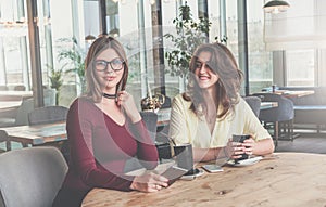 Two attractive young brunette women sit in cafe at table and drink coffee. Meeting friends at restaurant.