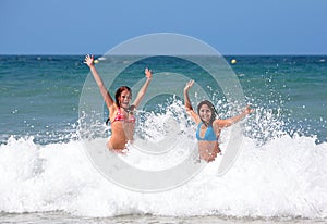 Two attractive young girl friends playing in the sea on vacation