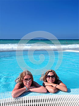 Two attractive young girls in a swimming pool on the beach