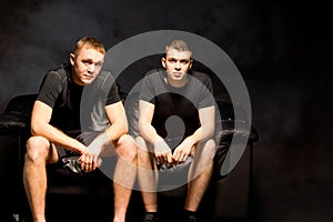 Two attractive young men on a black sofa