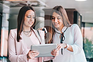 Two attractive young women sharing ideas on a digital tablet