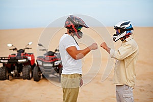 Two atv racers in helmets banging their fists