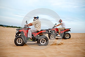 Two atv riders racing in desert sands