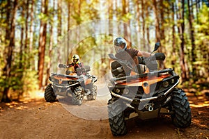 Two atv riders, speed race in forest, front view