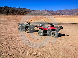 Two ATVs against the backdrop of mountains in the South Sinai Desert near Sharm El Sheikh Egypt. Red and black quadricycles are