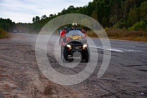 Two ATVs on an asphalt road park on the side of the road.