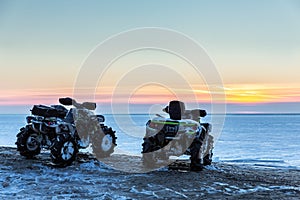 Two ATVs at sunset over the frozen north sea