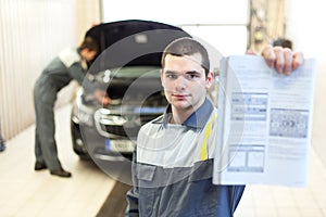 Two auto mechanics examining car with open hood