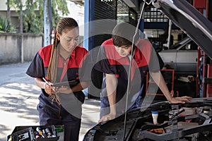 Two automotive mechanical partners check an EV car at a fixing garage.