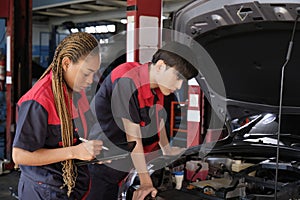 Two automotive mechanical partners check an EV car at a fixing garage.