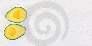 Two avocado halves with bright yellow pulp on white stone desk, view from above - wide banner space for text on right