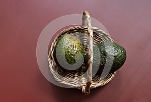 Two avocados on an antique wicker basket