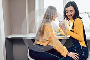 Two awesome girls gossipping while drinking coffee photo