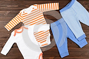 Two babies bodysuits and pants on wooden background. Baby clothe photo
