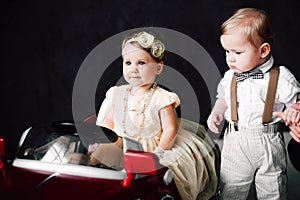 Two babies wedding - boy and girl dressed as bride and groom playing with toy car