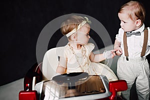 Two babies wedding - boy and girl dressed as bride and groom playing with toy car